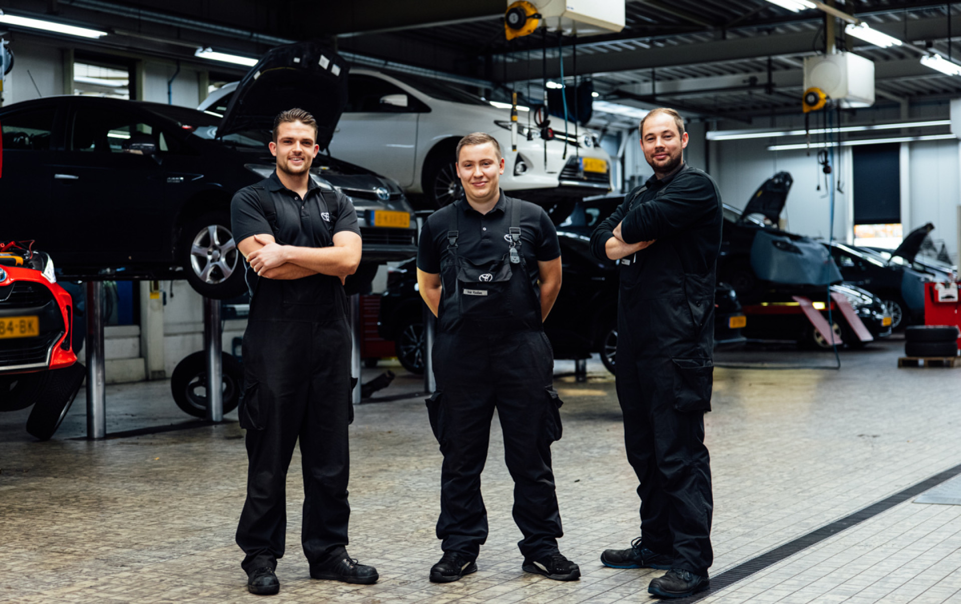 drie automonteurs poseren in de werkplaats